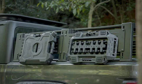 Two gray tool holders on a green vehicle with a forest background